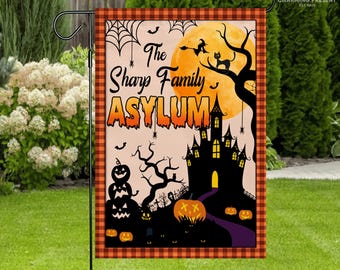 May include: A Halloween garden flag featuring a spooky scene with a haunted house, pumpkins, bats, and a full moon. The flag has the text "The Sharp Family Asylum" in orange and black, with a plaid border.
