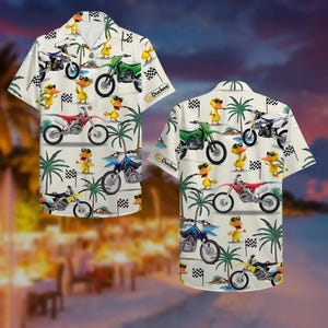 May include: Short-sleeved button-up shirt with a repeating pattern of cartoon ducks wearing sunglasses, motorcycles, palm trees, and checkered flags. The shirt is off-white with a relaxed fit.