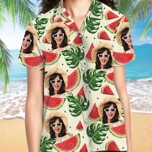 May include: A short-sleeved button-down shirt featuring an all-over print of watermelon slices, green tropical leaves, and a repeating photographic image of a person wearing a straw hat and white sunglasses against a cream-colored background.