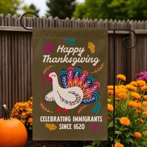 May include: A Thanksgiving garden flag with a turkey illustration and the text "Happy Thanksgiving Celebrating Immigrants Since 1620." The flag has a brown background with colorful leaves and a turkey with a vibrant tail.