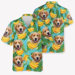 May include: A short-sleeved button-down shirt featuring a repeating pattern of golden retriever dog faces and yellow banana bunches set against a bright turquoise background with green tropical palm leaves throughout the fabric design.