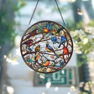 May include: A round stained glass window featuring colorful birds perched on tree branches. The birds are depicted in various colors, including blue, orange, and red, with a brown metal frame and a hanging chain.