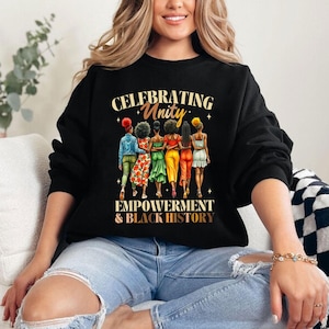 May include: Black sweatshirt with a graphic of five women walking together. The text "Celebrating Unity Empowerment & Black History" is printed on the sweatshirt.