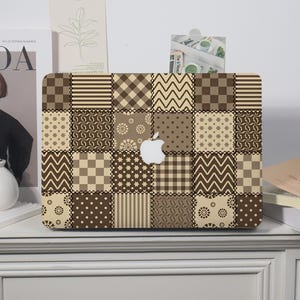 May include: A laptop skin featuring a patchwork design of various brown and beige patterns, including stripes, checks, zigzags, polka dots, and floral motifs. The design is arranged in a grid with a cutout in the center for the Apple logo.
