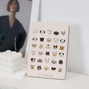 Peut inclure: Une boîte en métal rose avec une variété de visages de chiens imprimés dessus. La boîte porte l'inscription "be a happy dog" en bas.