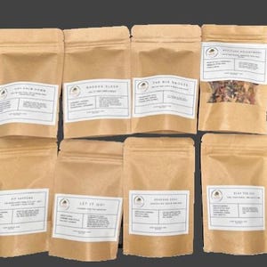 May include: An assortment of brown kraft paper pouches with white labels. The labels feature text and a circular logo. The pouches contain various herbal blends, with one pouch showing the contents. Text on the labels includes "Just Calm Down" and "Badass Sleep."
