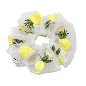 Könnte beinhalten: Ein weißer Mesh-Haargummi mit gelber Ananas-Stickerei.