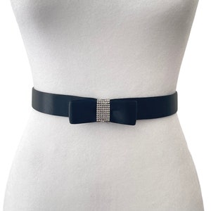 May include: A black satin belt with a large black bow accented with a row of clear rhinestones.
