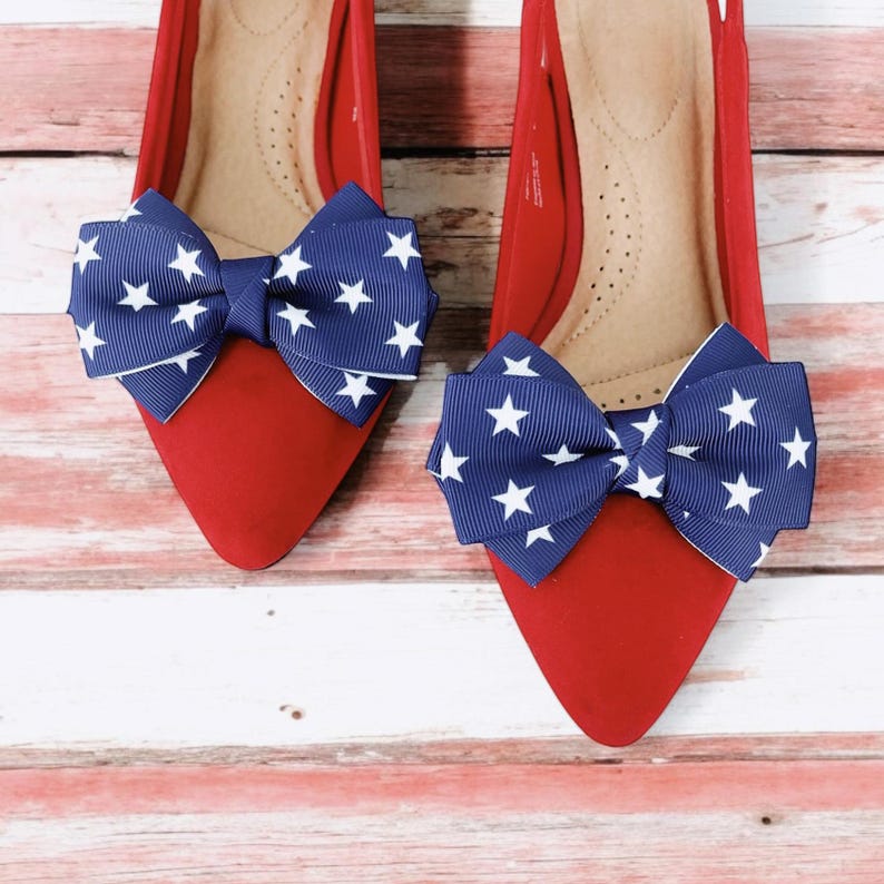 May include: A pair of red pointed-toe flats with a blue and white star patterned bow on each shoe.