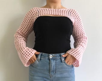 May include: A pink crocheted shrug with a wide, open neckline and long, bell sleeves.