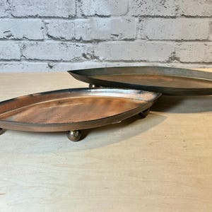 May include: A white ceramic mug with a black handle and the text "But First, Coffee" in a black, bold font. The mug is on a white surface.