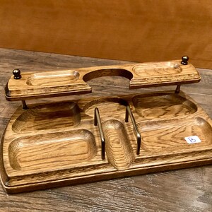 May include: A wooden desk tidy with multiple compartments and a raised shelf. The organiser is made of light brown wood with a visible grain pattern. It features several small, rounded compartments and metal accents.