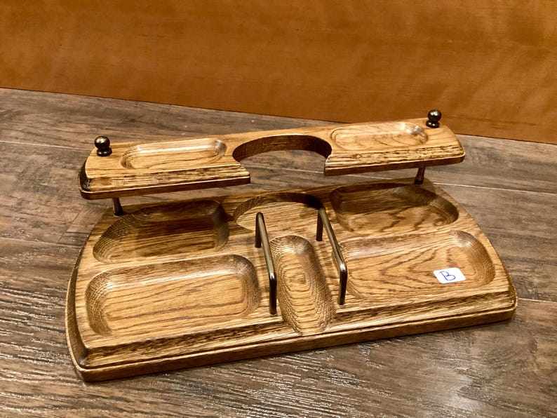 May include: A wooden desk tidy with multiple compartments and a raised shelf. The organiser is made of light brown wood with a visible grain pattern. It features several small, rounded compartments and metal accents.