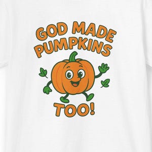 以下が含まれることがあります： 白いTシャツに、笑顔の顔と緑の葉を持つ漫画のカボチャのデザイン。オレンジ色の文字で「GOD MADE PUMPKINS TOO！」と書かれています。秋やハロウィーンに最適な、楽しく季節感のあるデザインです。