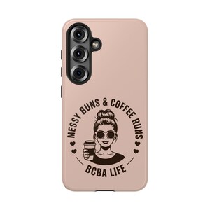 Könnte beinhalten: Hellrosa Handyhülle mit einer schwarzen Grafik einer Frau mit Sonnenbrille, Dutt und Kaffeetasse. Der Text lautet "Messy Buns & Coffee Runs" und "BCBA Life" in einem kreisförmigen Design.