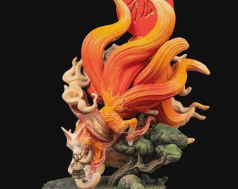 May include: A detailed figurine of a nine-tailed fox with vibrant orange and yellow fur, set against a red sun with Japanese characters. The fox is depicted with a bell and is surrounded by stylized smoke and a small tree on a circular base.