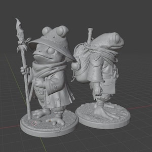 May include: Two gray frog figurines. One frog is wearing a hat and robe, holding a staff. The other frog has a backpack and is wearing a scarf and jacket. Both figurines are on round bases.