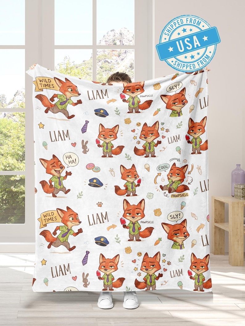 K&ouml;nnte beinhalten: Wei&szlig;e Decke mit einem sich wiederholenden Muster eines Cartoon-Fuchs-Charakters in verschiedenen Posen. Der Fuchs tr&auml;gt ein gr&uuml;nes Hemd und eine Krawatte. Die Decke enth&auml;lt auch den Namen "Liam" und S&auml;tze wie "Wild Times" und "Pawsicle".