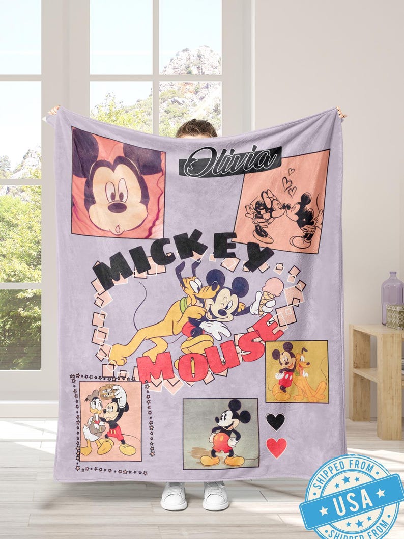 May include: A lavender Mickey Mouse blanket featuring multiple images of Mickey, Pluto, and Donald Duck. The blanket has the name "Olivia" in cursive and the words "Mickey Mouse" in large letters. The blanket is held up by a person.
