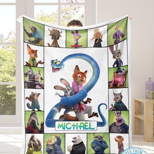 May include: A white blanket featuring characters from the animated movie Zootopia. The blanket has a central image of Nick Wilde, Judy Hopps, and a blue snake. The name "MICHAEL" is below the characters. Surrounding the central image are character portraits.