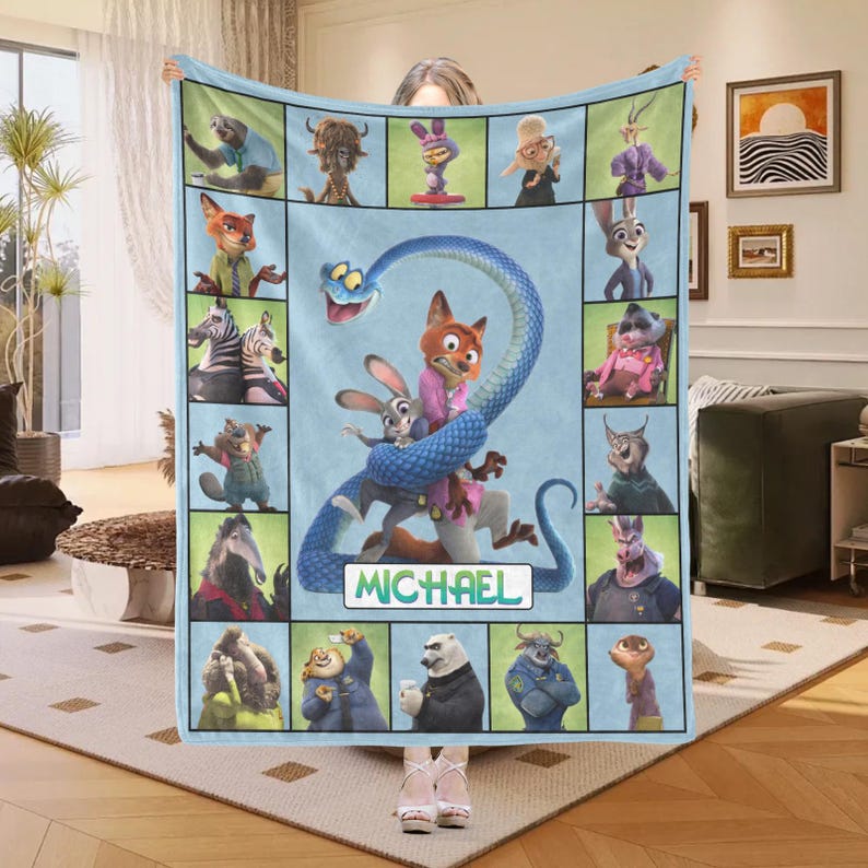 May include: A light blue fleece blanket featuring characters from the animated movie Zootopia. The blanket has a central image of Nick Wilde and Judy Hopps, with the name "MICHAEL" below. Surrounding the central image are various character portraits.