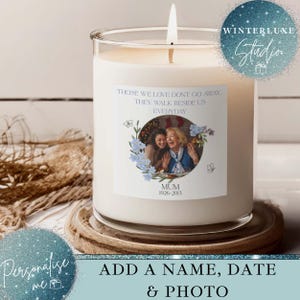 May include: A white candle in a clear glass jar, with a lit wick. The candle features a label with a photo and the text "THOSE WE LOVE DON'T GO AWAY. THEY WALK BESIDE US EVERYDAY." The label also says "MUM 1926-2013".