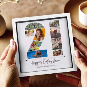 May include: A square white frame containing a photo collage shaped like the number 21. The collage features various candid images. Below the number, the text reads: Happy 21st Birthday Jessie WE LOVE YOU SO MUCH XX. The frame has a black inner border.