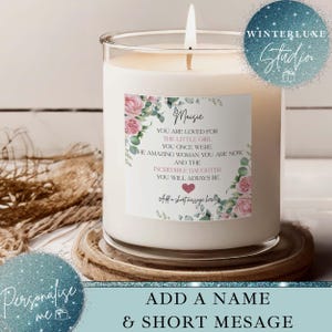 May include: A scented candle in a glass jar with a lit wick. The candle features a label with the name "Maisie" and a message with pink floral accents. The candle sits on a wooden coaster. The text reads "Add a name & short message".
