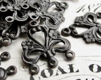 May include: A set of six antique-style metal embellishments with intricate floral designs and loop attachments. The embellishments are black and have a distressed finish.