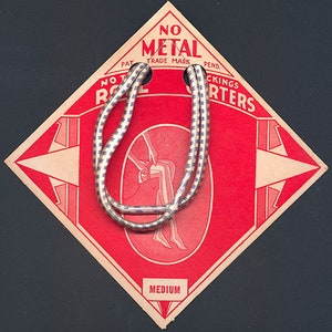May include: Red and white tag with the text "No Metal Trade Mark" and "No Rust Stockings Garters" in a white circle. The tag is diamond shaped and has a white elastic band with a black and white striped pattern.