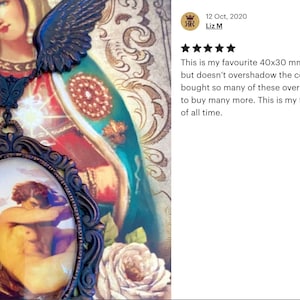 May include: A gold-toned pendant necklace with a cameo featuring a painting of a couple embracing. The cameo is set in a detailed ornate frame. The necklace is adorned with two angel wings.