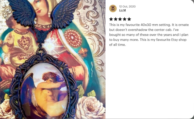 May include: A gold-toned pendant necklace with a cameo featuring a painting of a couple embracing. The cameo is set in a detailed ornate frame. The necklace is adorned with two angel wings.