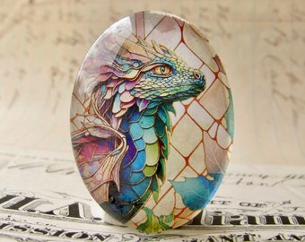 May include: A glass cabochon with a colorful stained glass dragon design. The dragon is blue, green, purple, and pink with a yellow eye. The background is a light beige with a grid pattern.