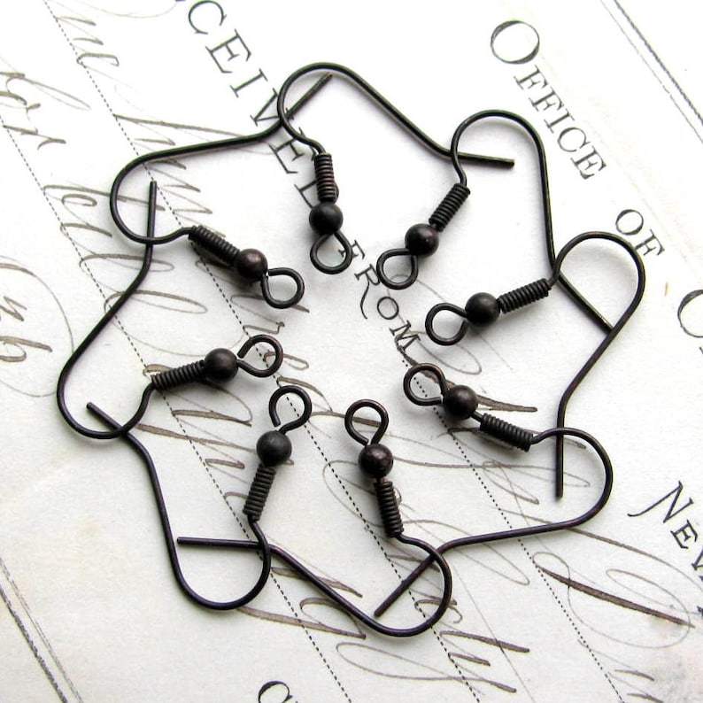 May include: Six antique bronze earring hooks with a spring clasp. The hooks are arranged in a circle on a white surface.