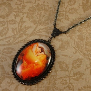 May include: A bronze necklace with a round cameo pendant featuring a painting of a woman in a red dress. The cameo is surrounded by a beaded border.