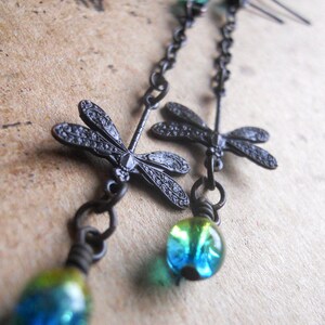 May include: Black metal dragonfly earrings with blue and green glass beads hanging from a chain.