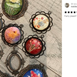 May include: Assortment of vintage-style metal frames with glass inserts. Some frames feature colorful images of a fairy, flowers, and a fish. The frames are perfect for crafting and jewelry making.