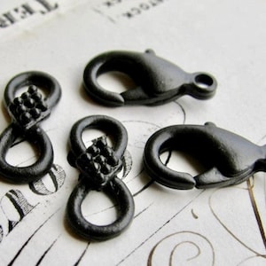 May include: Four black metal clasps, two are infinity shaped with a textured design and two are simple hook clasps.