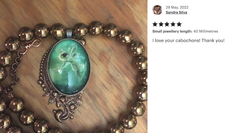 Op de afbeelding: Een koperen ketting met een ovale hanger in groen en goud met een afbeelding van een fee. De ketting is gemaakt met ronde, metalen kralen. De hanger is 40 millimeter lang. "Kleine sieradenlengte: 40 millimeter Ik hou van je cabochons! Dank je!"