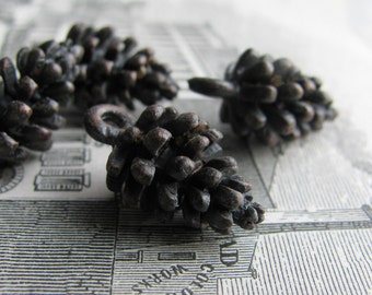 May include: Four small, dark brown, metal pine cone ornaments. The pine cones are detailed and realistic.