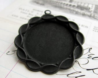 May include: Black metal pendant tray with a scalloped edge. The tray is designed to hold a round cameo or other decorative item.