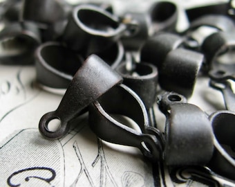 May include: A close-up of a pile of black metal pendant bails. The bails are all the same size and shape, and they have a smooth, matte finish.