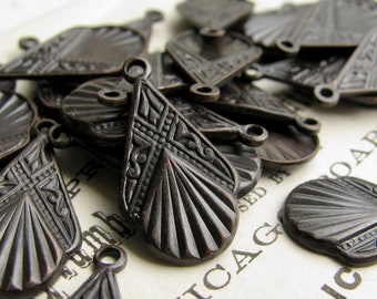 May include: A collection of antique bronze-colored teardrop-shaped charms. Each charm features intricate embossed patterns, including geometric shapes and radial lines. The charms have a small loop at the top for attaching to jewelry or other crafts.