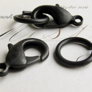 May include: Three black metal clasps, two are lobster claw clasps and one is a jump ring.
