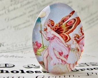 May include: A glass cabochon with a vintage illustration of three fairies with butterfly wings. The fairies are wearing pink and white dresses and are flying in a blue sky with white clouds. The cabochon is set in a silver ring.