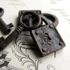 May include: Close-up of antique-style, dark brown metal keys and a small padlock. The keys have intricate details and are placed near the lock, suggesting a vintage or historical theme. The lock is square with a keyhole.