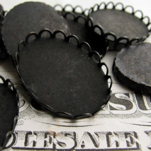 May include: A group of black metal round decorative embellishments with scalloped edges. The embellishments are arranged on a printed surface.