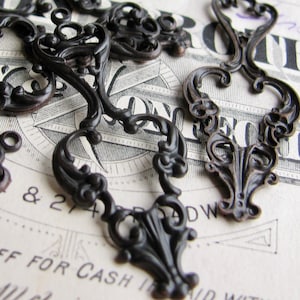 May include: A collection of ornate, black metal embellishments with intricate scrollwork designs. These decorative pieces are perfect for adding a touch of vintage charm to crafts, jewelry, or home decor.