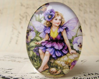 May include: An oval glass cabochon featuring a colorful illustration of a fairy with blonde hair, purple wings, and a purple and yellow petal dress, sitting among pansy flowers with a small snail on the ground near the fairy's feet.
