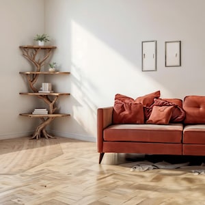 K&ouml;nnte beinhalten: Ein h&ouml;lzernes Eckregal mit baumartigem Design, das vier Regale mit B&uuml;chern und Pflanzen aufweist. Ein rostfarbenes Sofa mit mehreren Kissen befindet sich in der N&auml;he. Der Raum hat einen Parkettboden und eine minimalistische &Auml;sthetik.